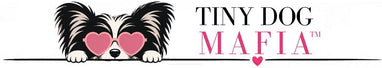 A stylized logo featuring a small black-and-white dog peeking over a line with pink heart-shaped glasses, next to the text 'TINY DOG MAFIA' in black and pink on a white background.